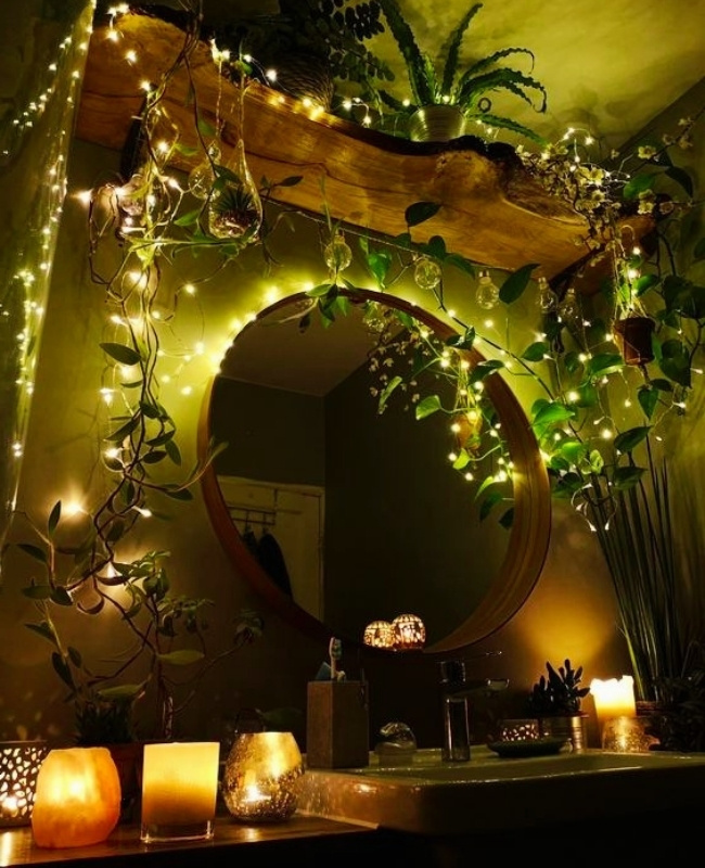 round bathroom mirror decorated with candles and string lights with faux vines