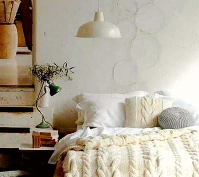 white farmhouse pendant light hanging on top of a white bed
