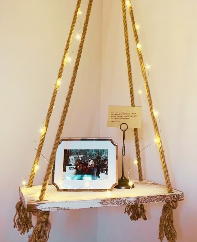 floating wooden shelf with picture frame and trinket place on the pallet, the macrame holder is decorated with fairy lights