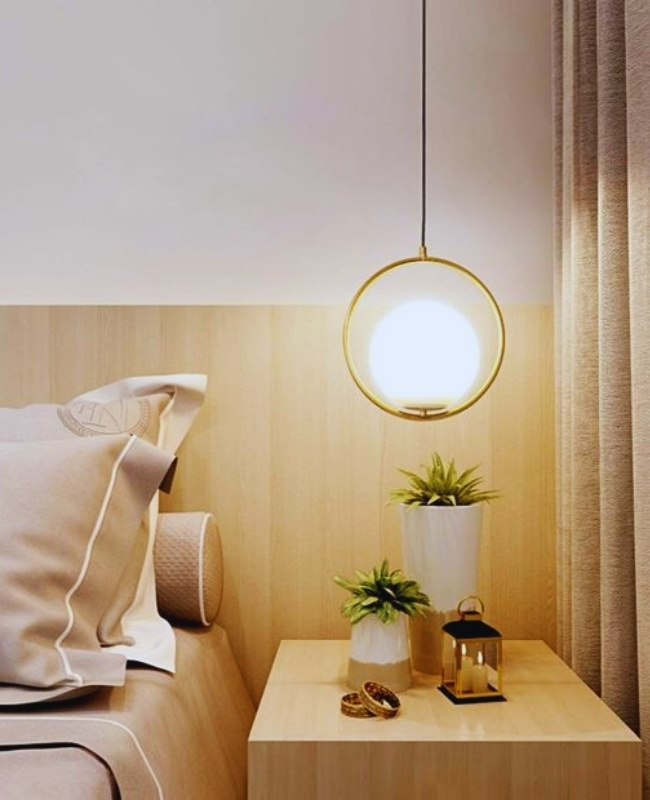 circular pendant light attached to a gold ring hanging above the bedside table