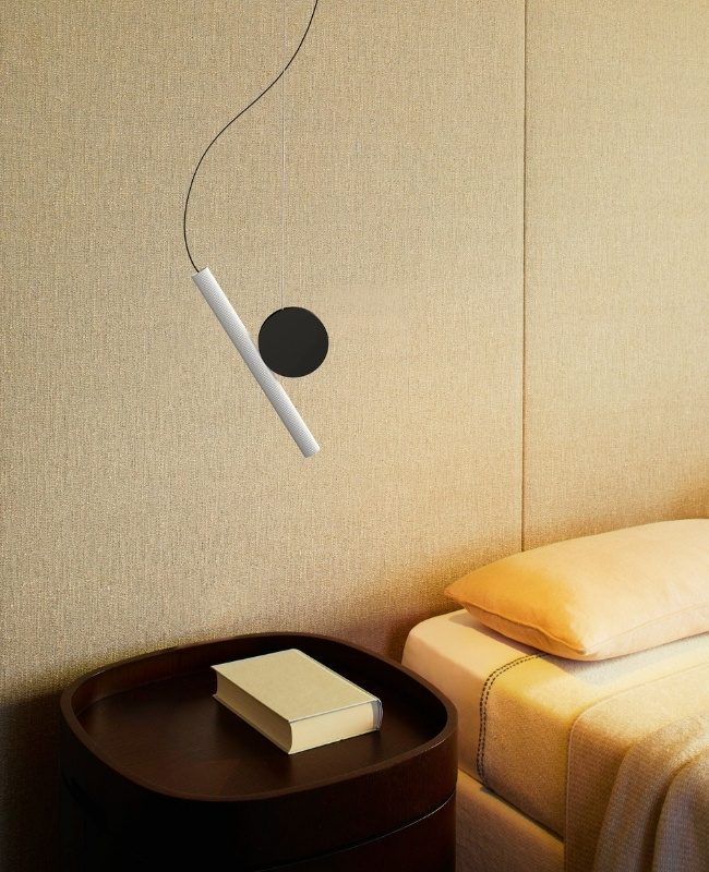 sleek nordic pendant light hanging on top of a dark brown bedside table